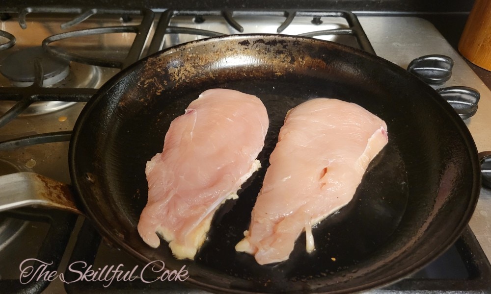 Raw chicken breast on carbon steel pan